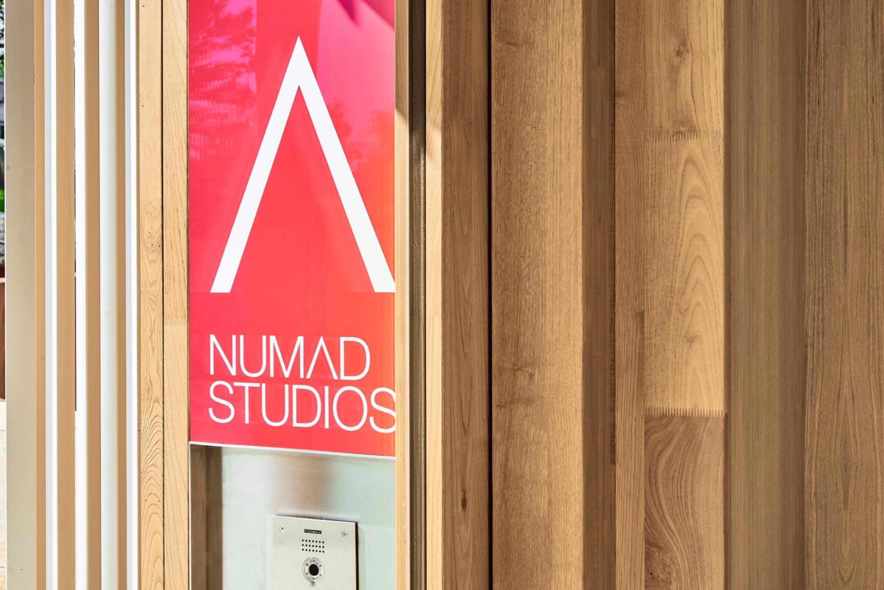 Eine Holztür mit einem roten Schild, auf dem 'NUMAD STUDIOS' steht.