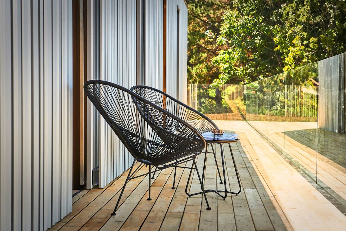 A wooden deck with two black wire-framed chairs and a small table.