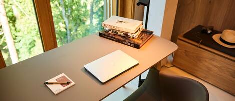 A desk with a laptop, a notebook, and a stack of books.