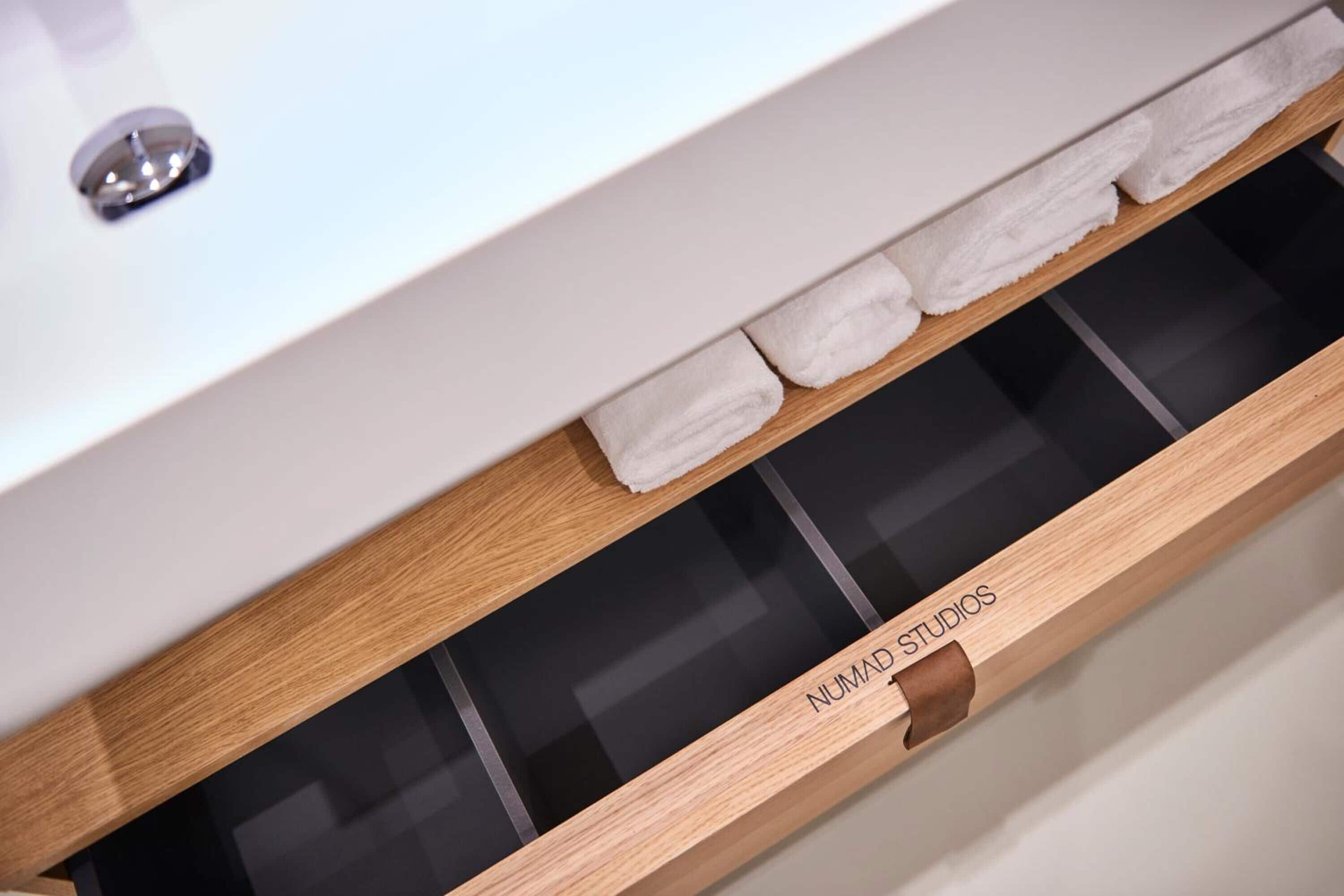 A wooden drawer with a label "NUMAD STUDIOS" and a white towel on top.