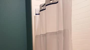 A bathroom with a toilet, a shower curtain, and a bathtub.