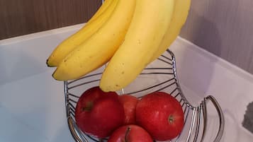 Una cesta de frutas con plátanos y manzanas sobre una superficie blanca.