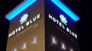 Een hotel genaamd 'Hotel Blue' met een modern ontwerp, herkenbaar aan verlichte signage en ramen.