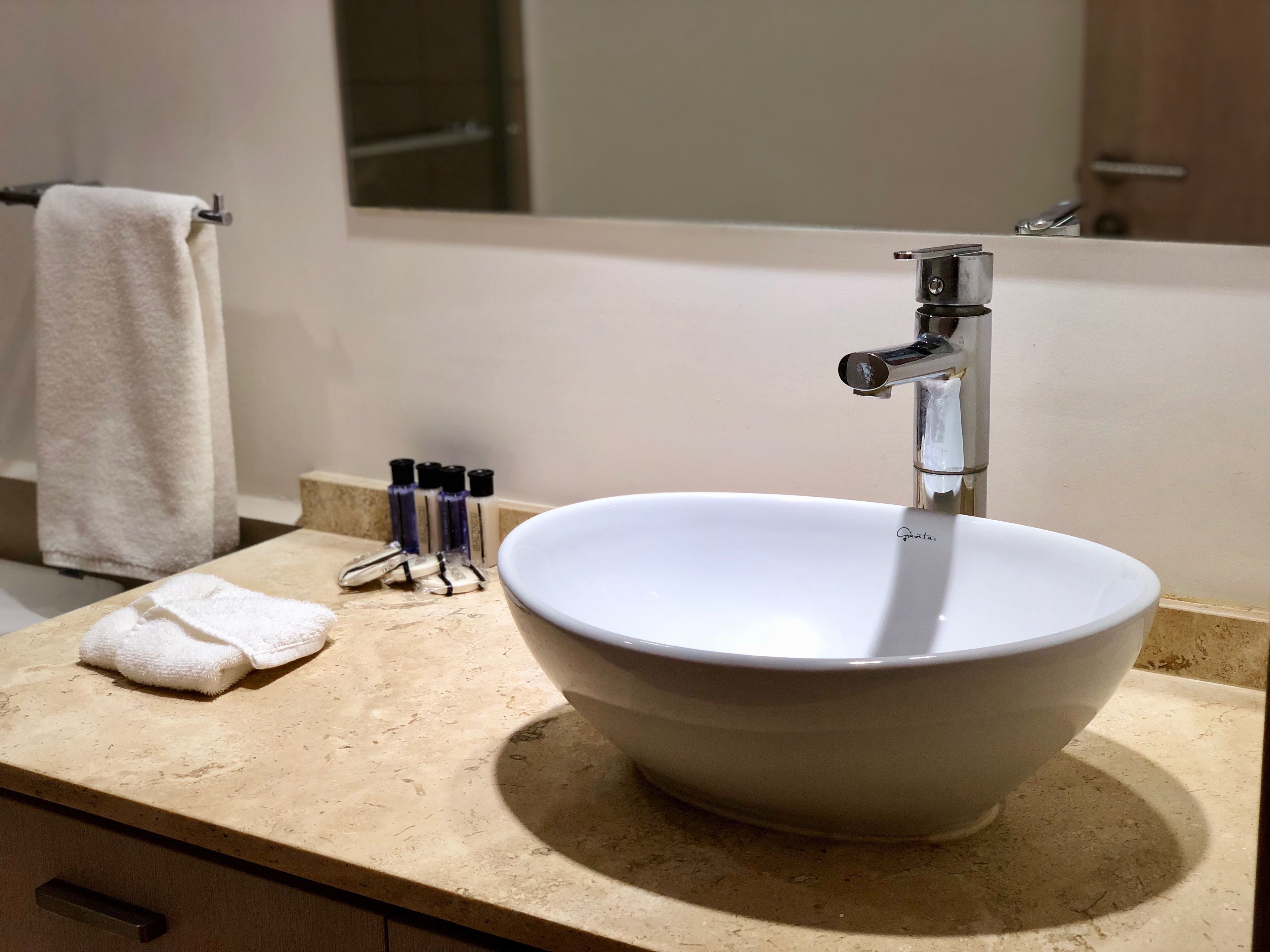 Un bany amb un lavabo blanc, un mirall i una barra de tovalloles.