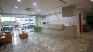 A hotel reception area with a marble floor, a reception desk, and a view of the outside. - Hotel Ave Inn Mazatlán (Mazatlán)