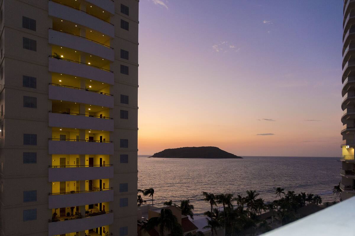 A high-rise hotel with multiple balconies overlooking a beach and ocean.
