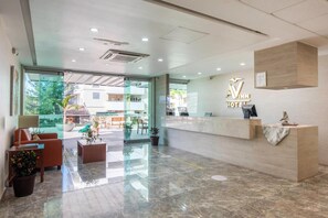 A hotel reception area with a modern design, including a reception desk, seating area, and a view of the outdoor space. - Hotel Ave Inn Mazatlán (Mazatlán)