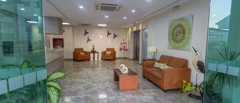 A spacious lobby with a marble floor, two sofas, a coffee table, and decorative wall art.