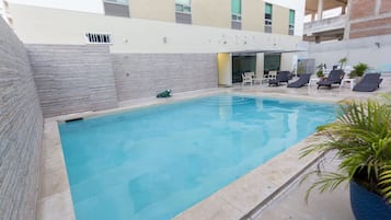 Una piscina al aire libre, sillones reclinables de piscina