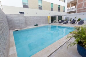 Una piscina al aire libre, sillones reclinables de piscina