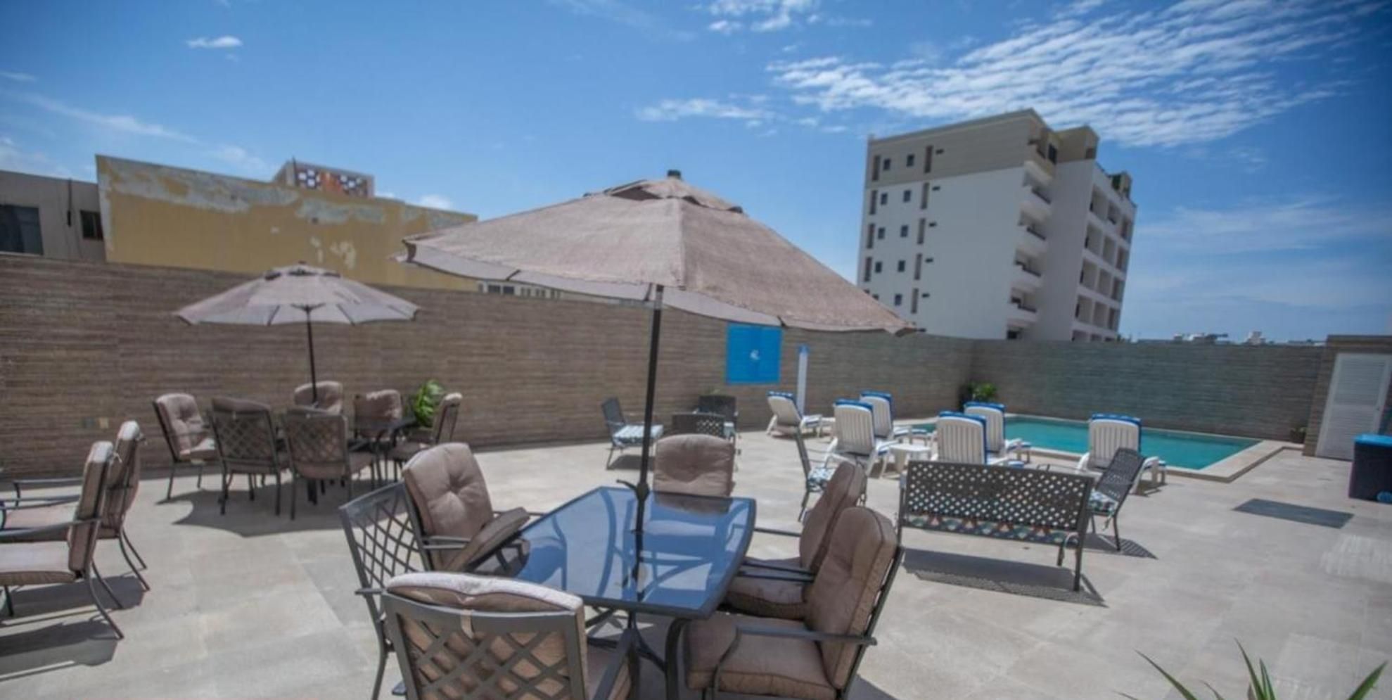 An outdoor patio area with seating arrangements, a pool, and a view of a cityscape.