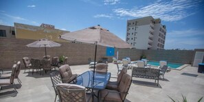An outdoor patio area with seating arrangements, a pool, and a view of a cityscape.