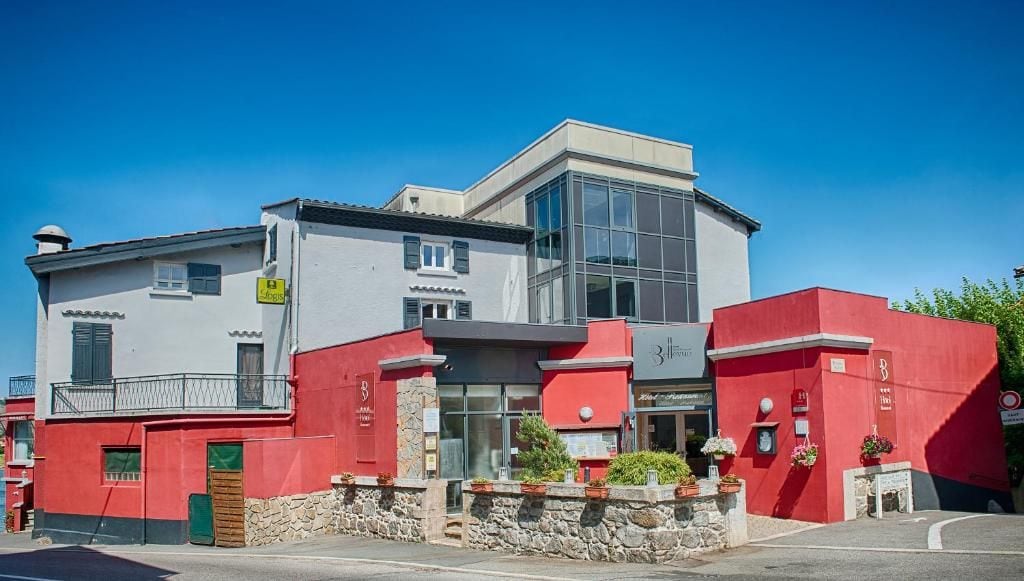 A modern building with a red and white facade, large windows, and a stone base.
