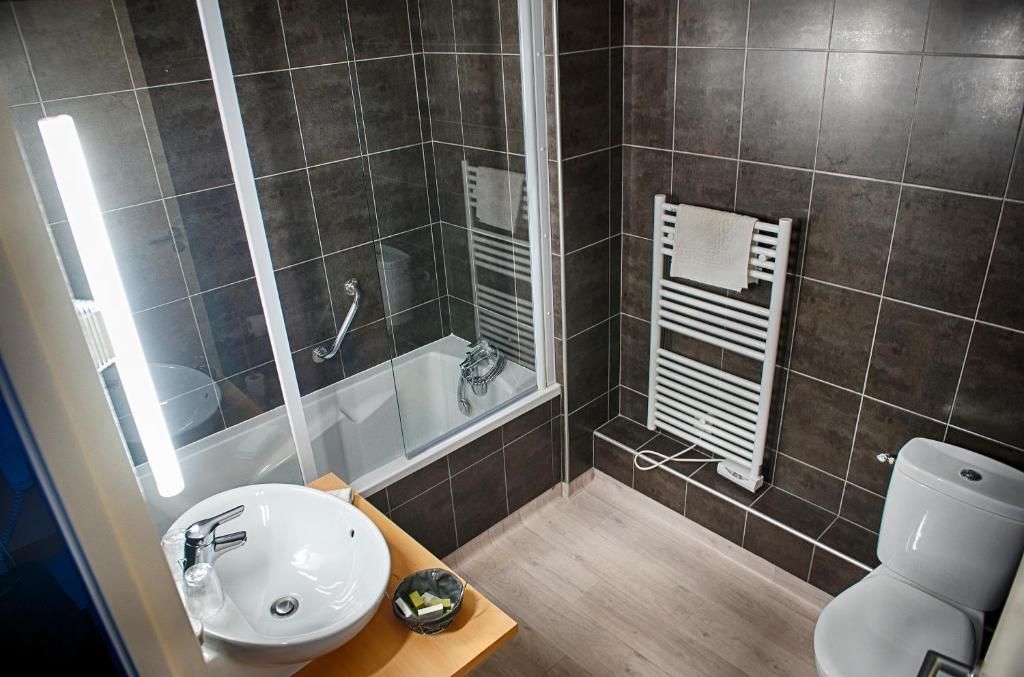 Un baño moderno con ducha envuelta en vidrio, un lavamanos blanco y un inodoro.