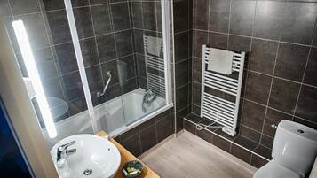 Un baño moderno con ducha envuelta en vidrio, un lavamanos blanco y un inodoro.