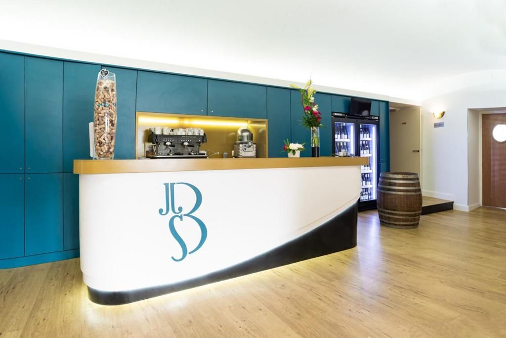 A reception desk with a logo, a coffee machine, and a minibar.