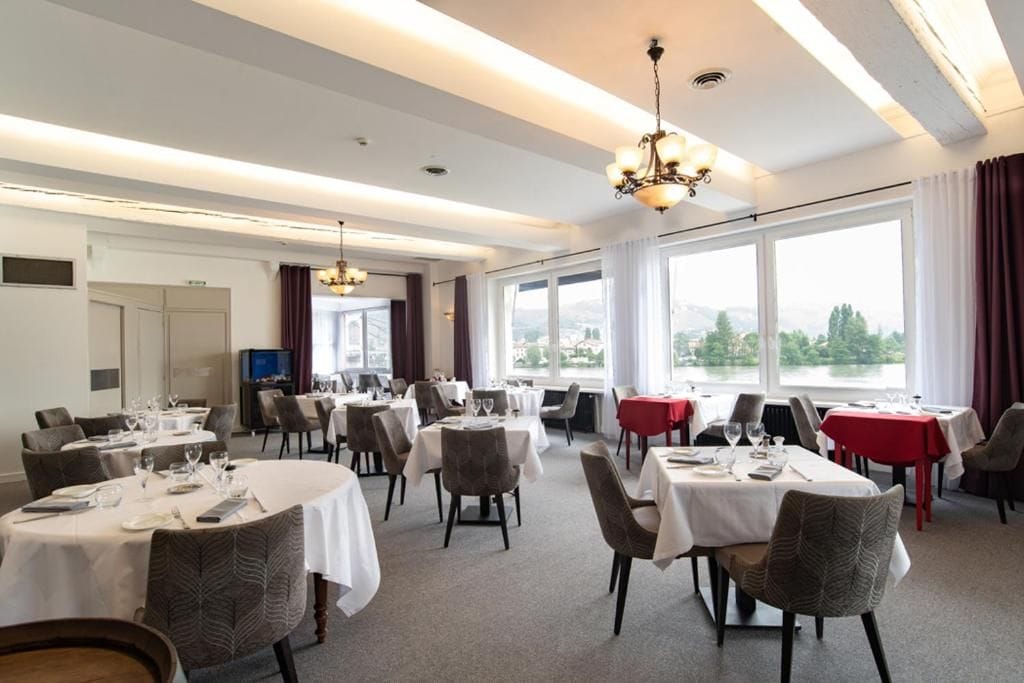 A dining area with round tables, chairs, and a chandelier.