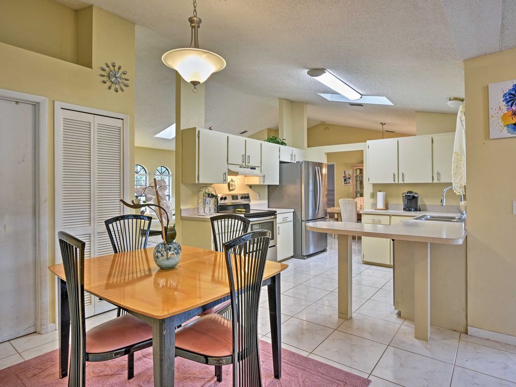 Une cuisine spacieuse avec un coin repas, comprenant un îlot central, des appareils modernes et un lustre.
