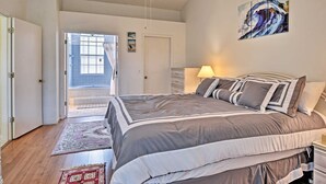 A bedroom with a large bed, a bedside table, a lamp, and a painting on the wall. - Avis House (Palm Bay)