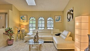 A living room with a beige sofa, a glass coffee table, and a potted plant. - Avis House (Palm Bay)