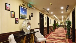 Un pasillo de hotel con cuadros enmarcados, un espejo decorativo grande y una alfombra estampada.
