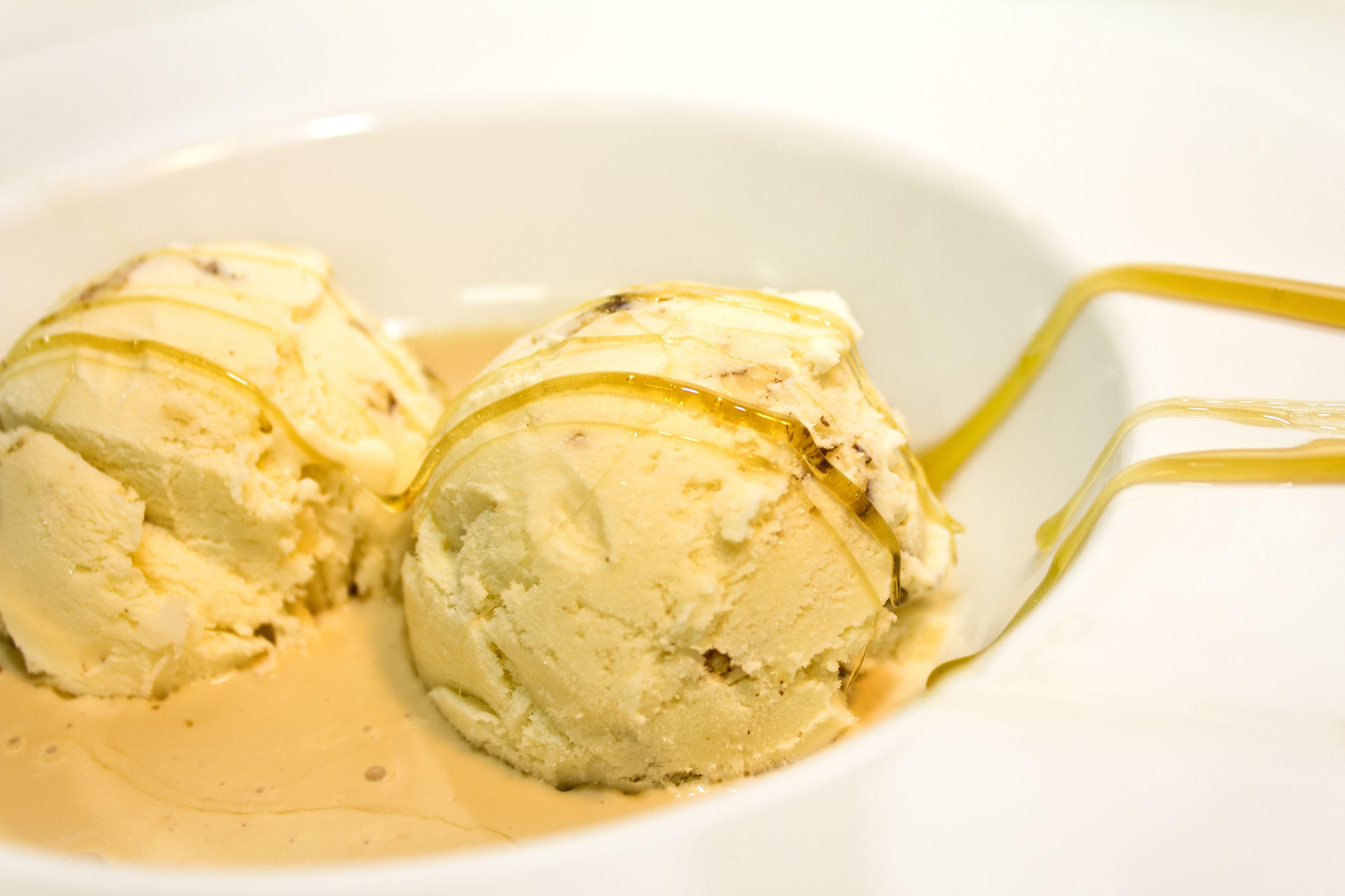 Un tazón de helado de vainilla con salsa de caramelo.