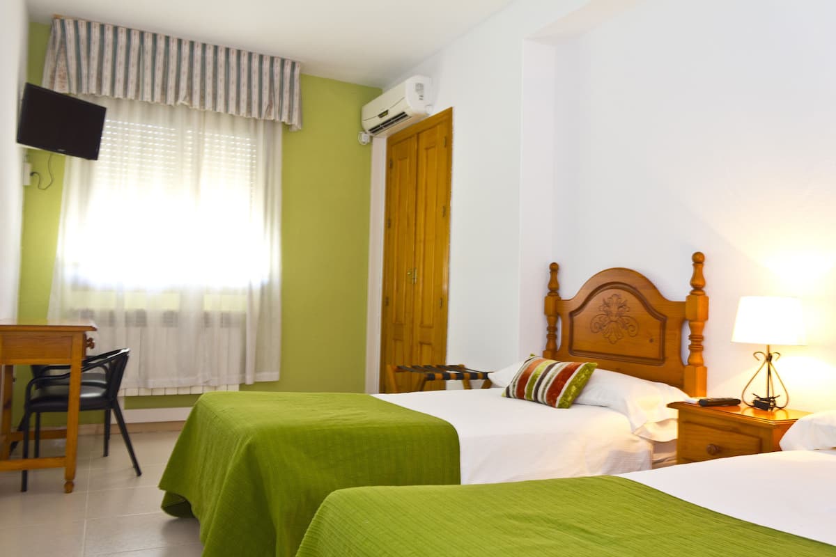 Una habitación de hotel con dos camas, televisión, escritorio y una silla.