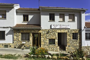 Un edificio de dos pisos con fachada de piedra y un letrero que dice "Hostal Restaurante El Mirador".