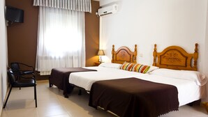 Habitación de hotel con dos camas, una silla, un televisor y un equipo de aire acondicionado.