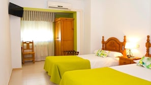 Habitación de hotel con dos camas, un armario de madera, un televisor y una silla.