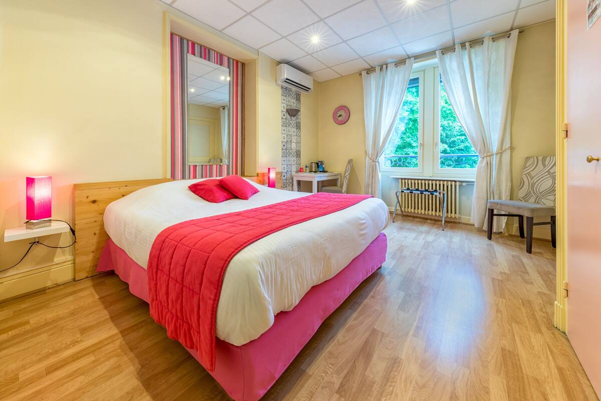 Un dormitorio con una cama grande, un escritorio, una silla y una ventana con cortinas.