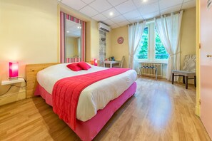 Un dormitorio con una cama grande, un escritorio, una silla y una ventana con cortinas.