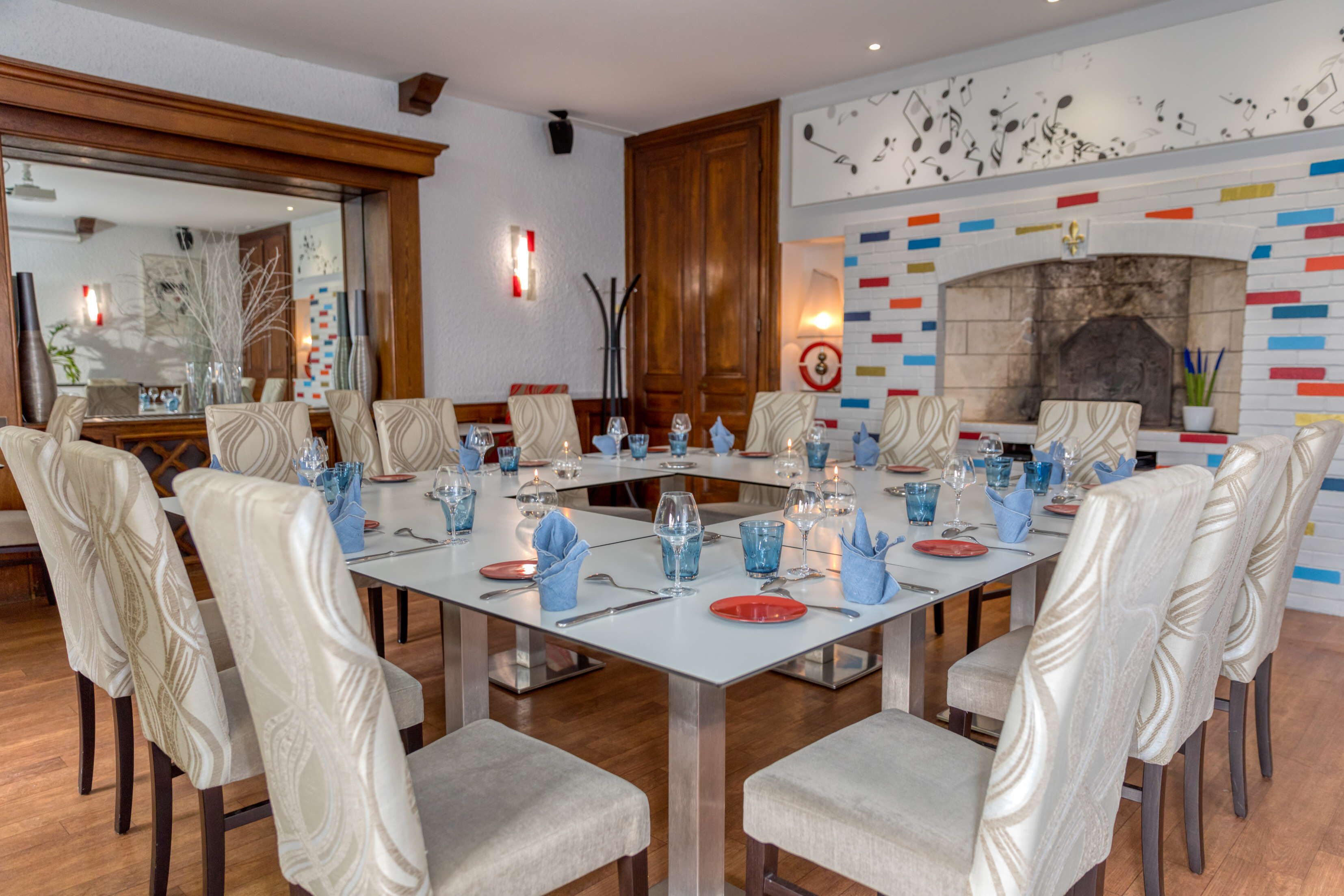 Un comedor con una mesa larga dispuesta para una comida, rodeado de sillas tapizadas.