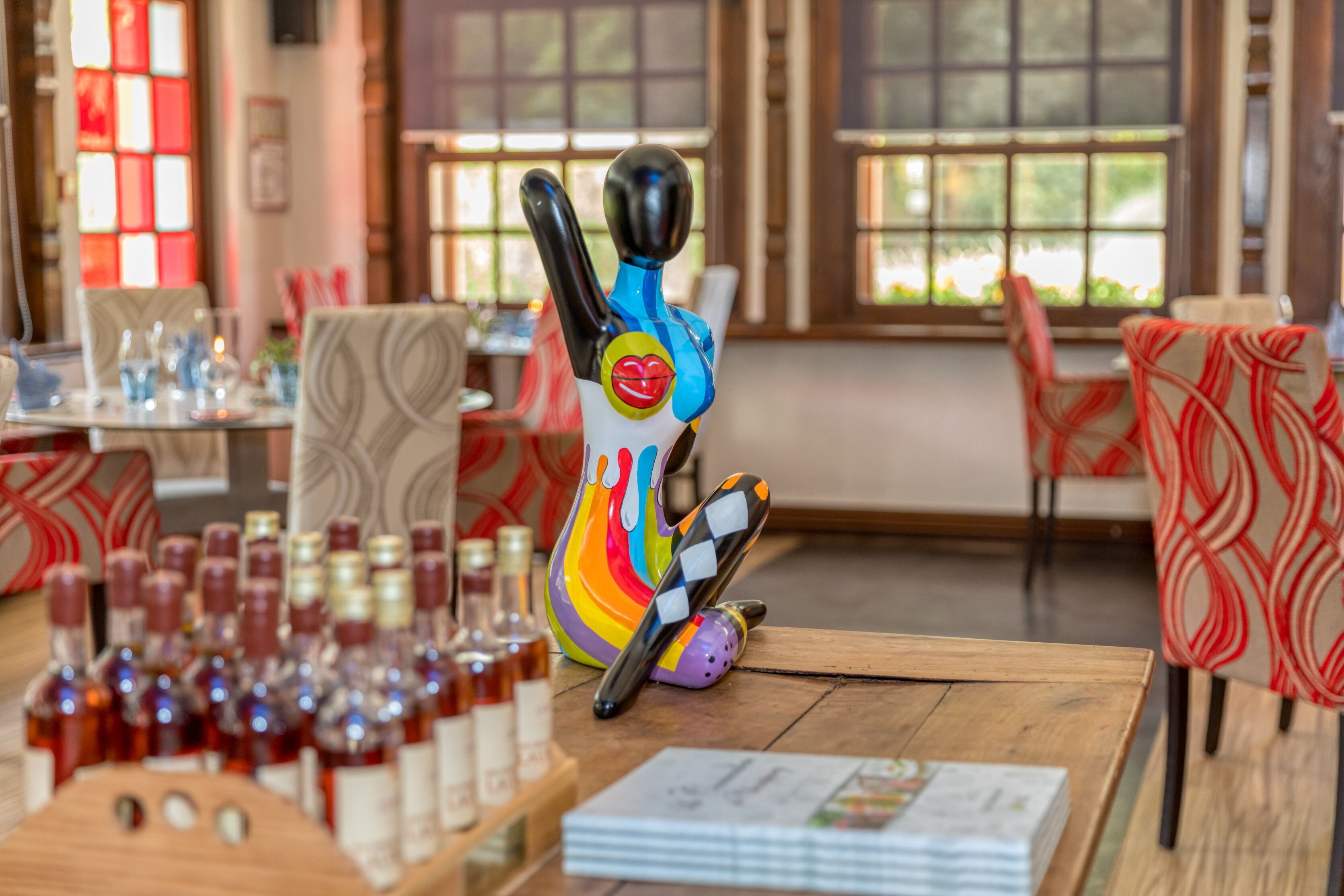 A dining area with wooden tables, chairs, and a colorful decorative piece on the table.