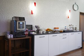 Una cocina moderna con una cafetera, un frutero y diferentes utensilios de cocina sobre la encimera.