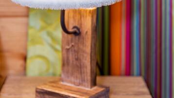 Eine hölzerne Tischlampe mit weißem Lampenschirm auf einer Holztischplatte.