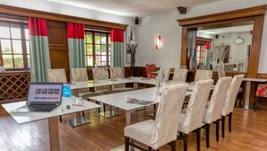 Une salle de conférence avec un ordinateur portable sur une table, plusieurs chaises et un grand miroir au mur.