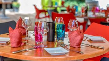 Una mesa redonda con varios vasos de colores y algunos adornos rojos.