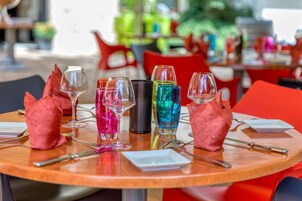 Una mesa redonda con varios vasos de colores y algunos adornos rojos.