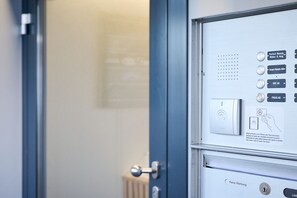 A hotel room door with a control panel featuring buttons for room services and a keycard reader. - Smart Hotel Kreisel -- Self Check-in (Lachen)