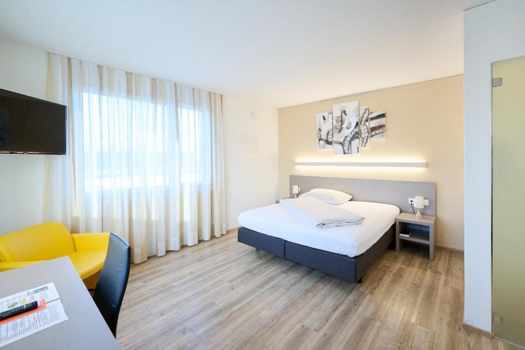 Ein Hotelzimmer mit Bett, Schreibtisch, Stuhl und Fernseher.