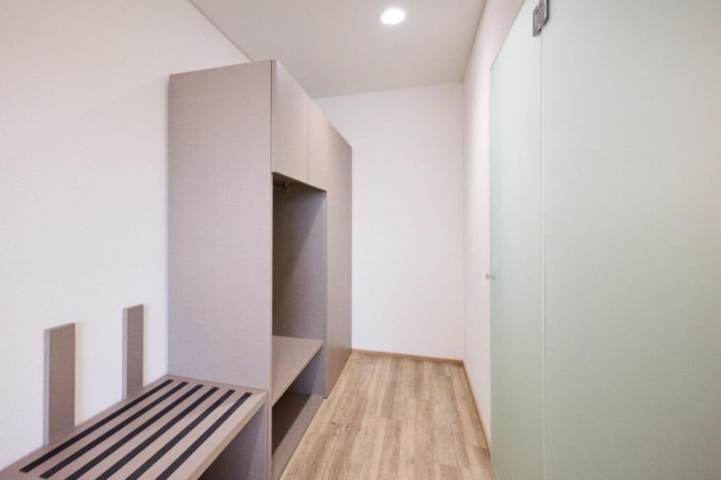 A narrow hallway with a bench and a wardrobe.