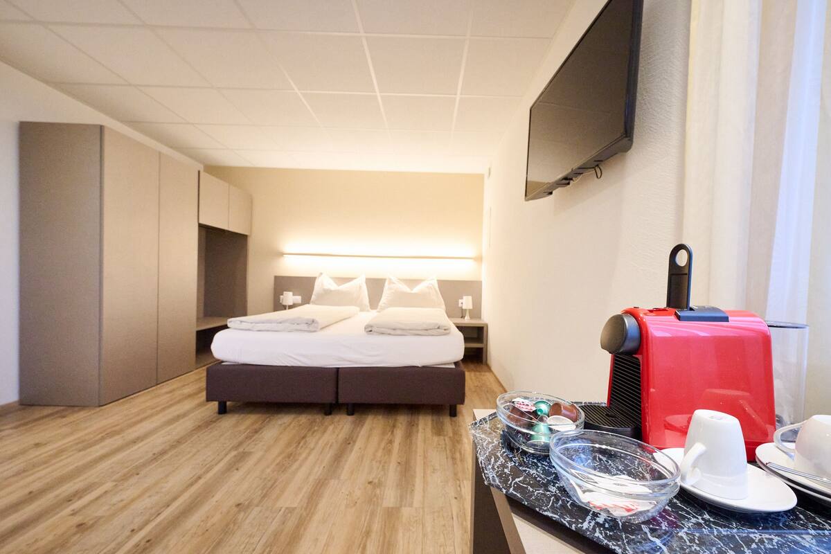 A modern hotel room with a bed, bedside tables, a flat-screen TV, and a coffee maker.