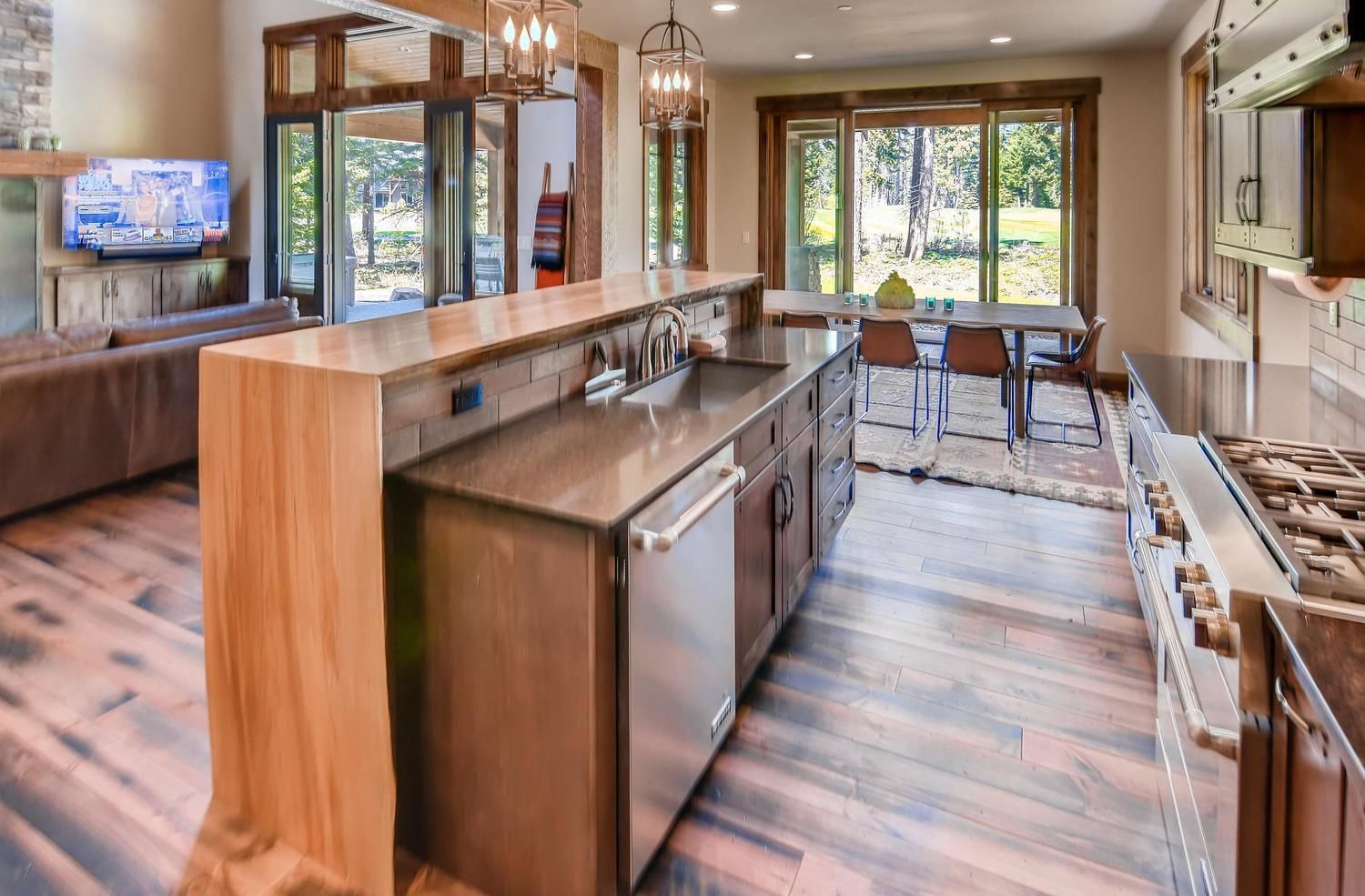 A modern kitchen with a large island, stainless steel appliances, and a dining area with a view of the outdoors.