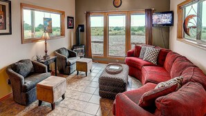 A cozy living room with a fireplace, comfortable seating, and large windows offering a view of the outdoors. - Beach Haven (Ocean Park)