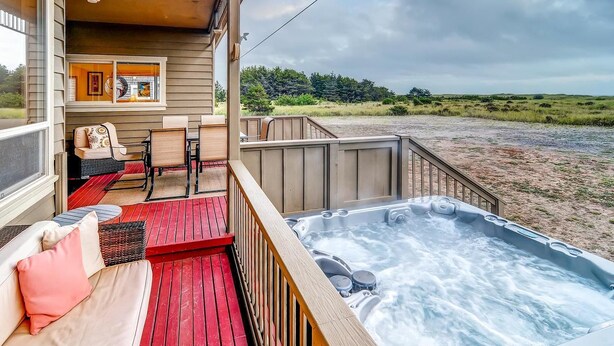 A cozy outdoor deck with a hot tub, seating area, and a view of the beach. - Beach Haven (Ocean Park)