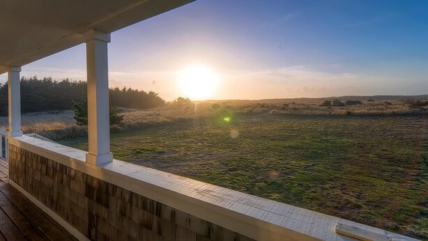 A wooden deck with a view of a sunset over a grassy field. - Beachwood Estate (Ocean Park)