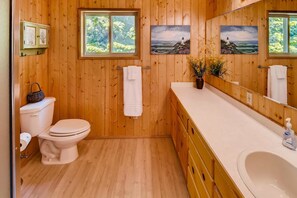 A wooden-paneled bathroom with a toilet, sink, and large mirror.