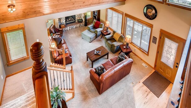 A spacious living area with a stone fireplace, leather sofas, and a wooden staircase. - Cascade Mountain Villa (Cle Elum)