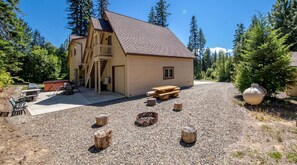A cabin with a sloped roof, a covered patio, and a fire pit.